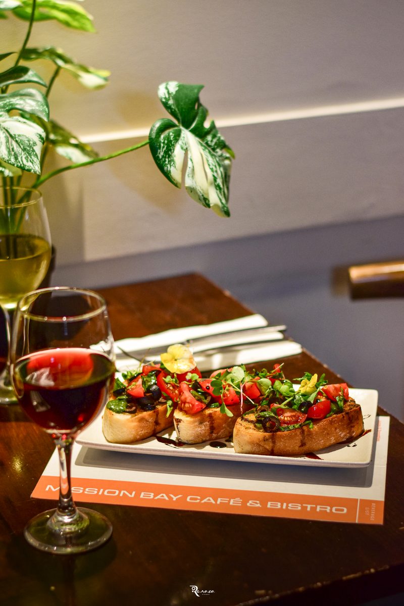Grilled bruschetta with tomato and olives, served with a glass of red and white wine, on the Mission Bay Cafe dinner menu